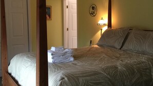 Una cama con dosel, una pila de toallas, una lámpara de noche y un ventilador de techo en una habitación con paredes amarillas.