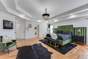 A modern bedroom with a green upholstered bed, a black bench, and a wooden floor. - Atlanta Luxury Home (8bedrooms)  (Atlanta)