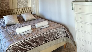 Un dormitorio con una cama, un televisor sobre una cómoda y una lámpara fijada a la pared.