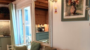 Una habitación acogedora con cama, espejo, un cuadro y una kitchenette.