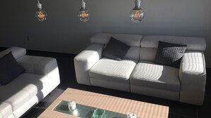 Una sala de estar moderna con un sofá, una mesa de centro e iluminación colgante.