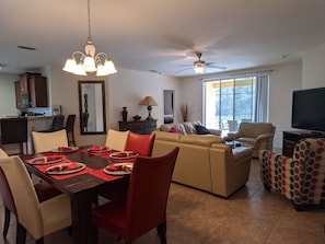 A dining area with a table set for four, a sofa, and a television in a living room.