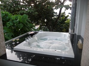 A hot tub with a glass top, surrounded by greenery, and a window on one side.