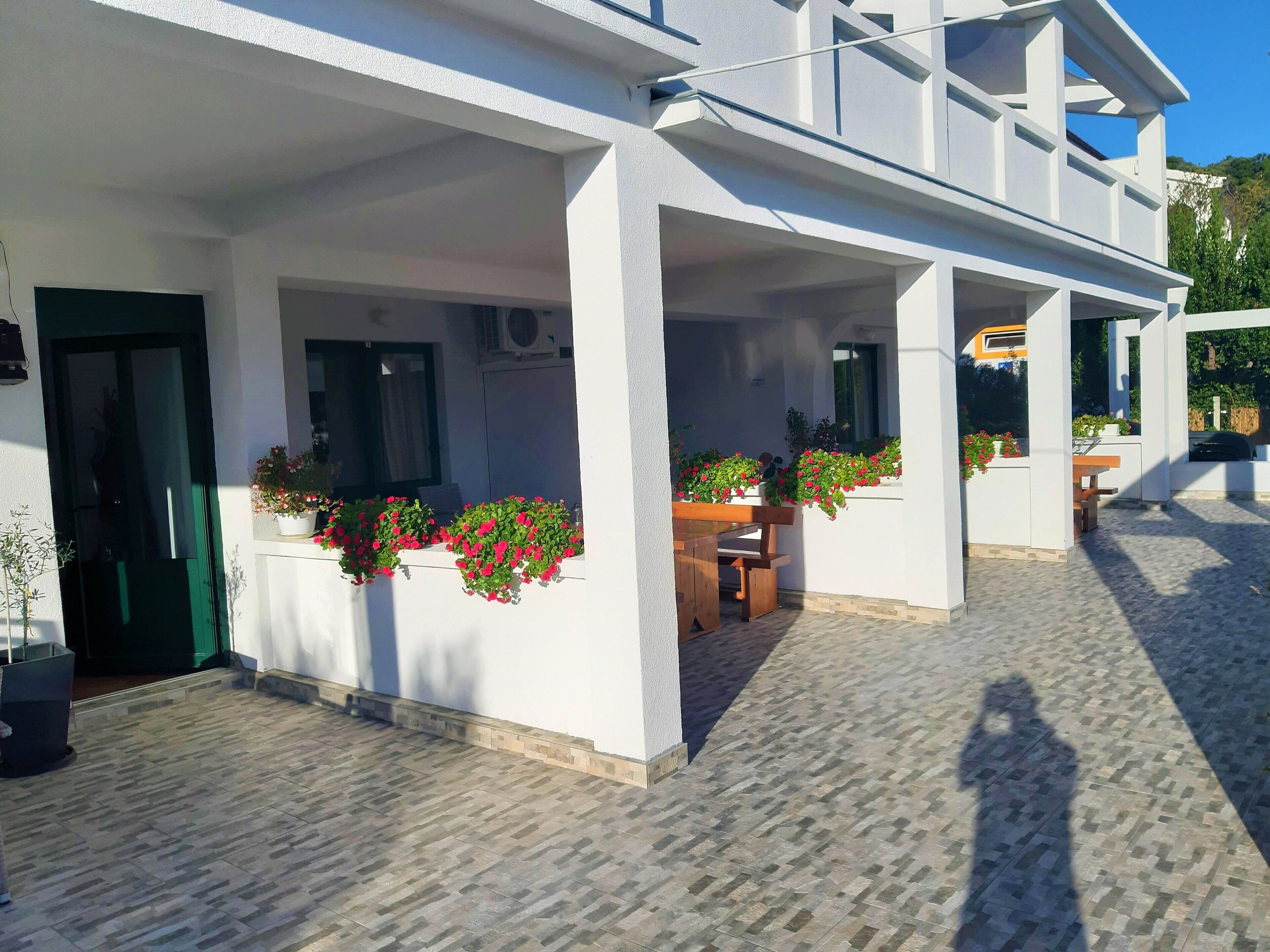 A building with a covered outdoor area, potted plants, and a tiled floor.