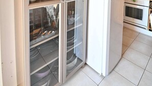 Una cocina con refrigerador empotrado, un armario de vidrio con vajilla y techo de madera.