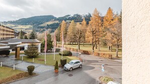 L’entrée d’un hôtel avec un espace de stationnement, un bâtiment à plusieurs étages et, en arrière-plan, une vue sur les arbres et les collines aux couleurs automnales.