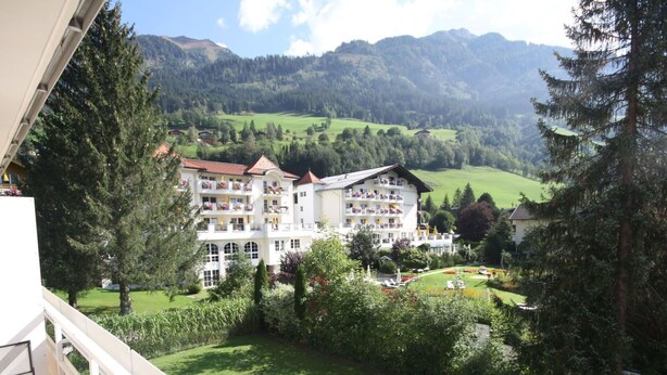 Un hôtel doté de nombreux balcons, d’un jardin et offrant une vue sur un paysage montagneux.