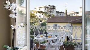 A balcony with white metal chairs and tables, potted plants, and a view of buildings in the background. - ARTWORK APARTMENT IN FLORENCE CITY CENTER (Firenze)