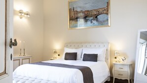 Une chambre à coucher bien aménagée, avec un grand lit, des tables de chevet, un tableau représentant un pont et des appliques murales.