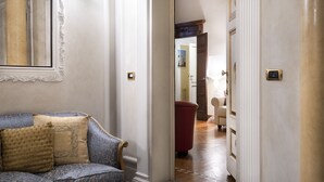 Un couloir avec un canapé bleu, un fauteuil rouge et des colonnes blanches.