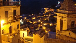A nighttime view of a historic town with illuminated buildings and a prominent church tower. - Marina di Ragusa - House with garden (Santa Croce Camerina)