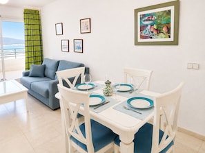 A dining area with a table set for two, a blue sofa, and a view of the outdoors. - Calpe: apartment/ flat - Calpe (Calpe)