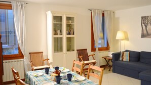 A dining area with a table set for four, surrounded by wooden chairs. A cabinet with glass doors is visible in the background.