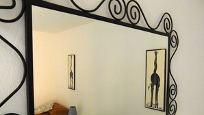 A room with a bed, a small table, a lamp, and a giraffe picture on the wall.