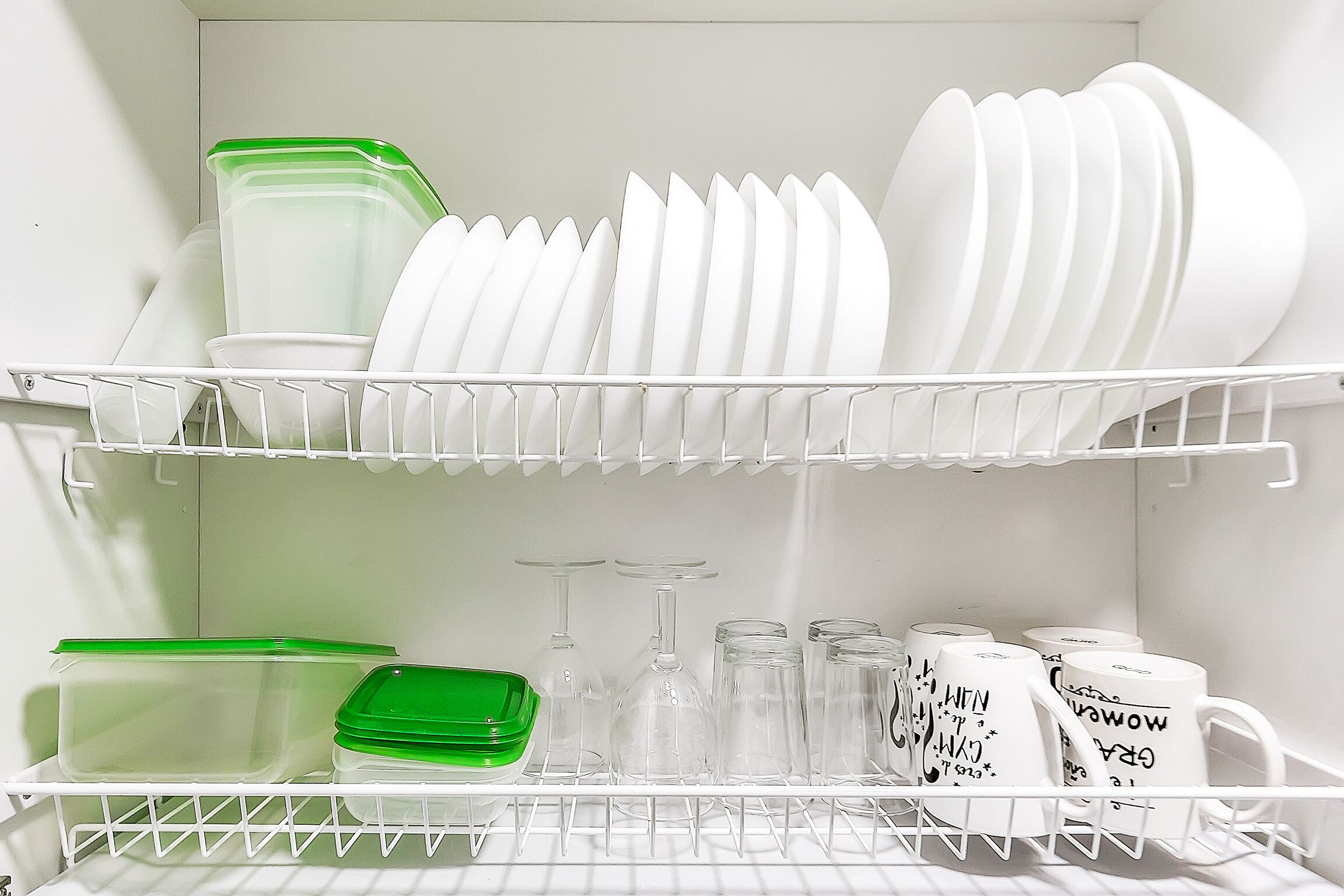 A kitchen with white dish racks and storage containers.