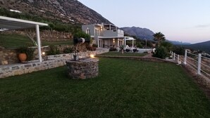 Une maison moderne dotée d’une terrasse en pierre, d’un espace salon extérieur et offrant une vue sur les montagnes.