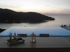 A terrace with a view of a calm sea and mountains at dusk. - Crete Lassithi Holiday 'Villa Tholos Crete'in Kavousi Beach Tholos Private Pool  (Lassithi)