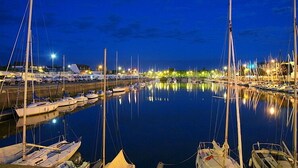 En småbåtshamn i mörkret, med båtar förtöjda och ljus som speglas i vattnet.