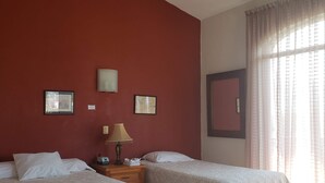 Une chambre d’hôtel avec deux lits, un ventilateur de plafond et une fenêtre avec des rideaux.