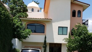 Une maison à deux étages avec une voiture garée dans l’allée.