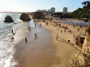A beach with people, umbrellas, and buildings in the background. - Lovely Apartment Alvor With Sea Views And Roof Top Communal Pool (Alvor)