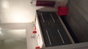A bathroom with a white sink, a mirror, and a red towel hanging on a rack. - To explore the Christmas Markets in Alsace! (Neuf-Brisach)