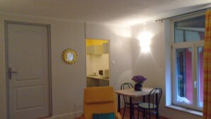 A dining area with a table and chairs, a mirror, and a window with curtains. - To explore the Christmas Markets in Alsace! (Neuf-Brisach)