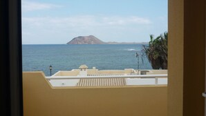 Un balcón con vista al mar y una montaña distante.