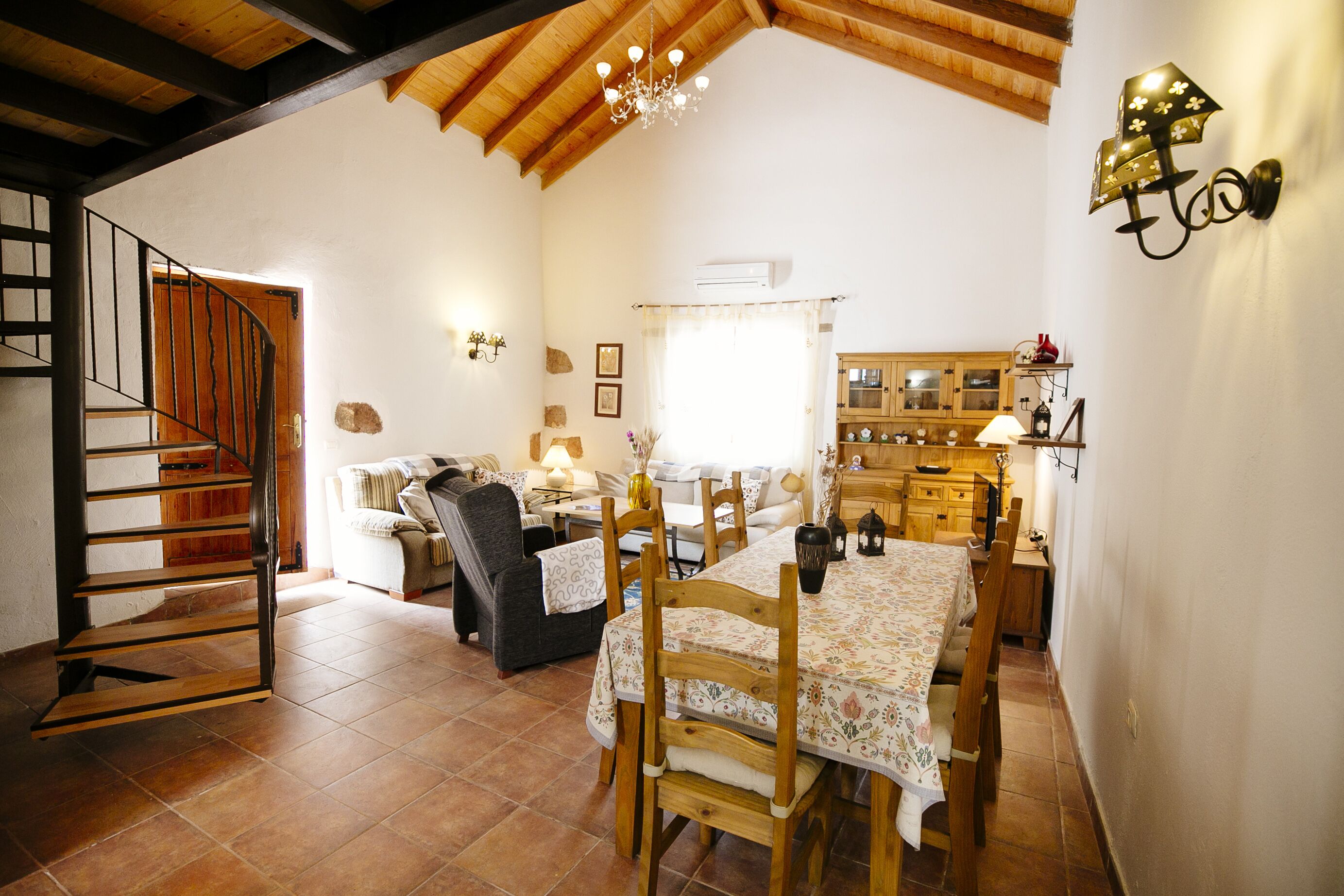 Een gezellig interieur met een eethoek, houten trap en een keuken.