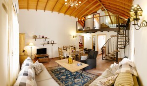 A spacious living room with a high ceiling, a wooden staircase, and a balcony. - Beautiful traditional house in rural surroundings (Santa Lucía de Tirajana)