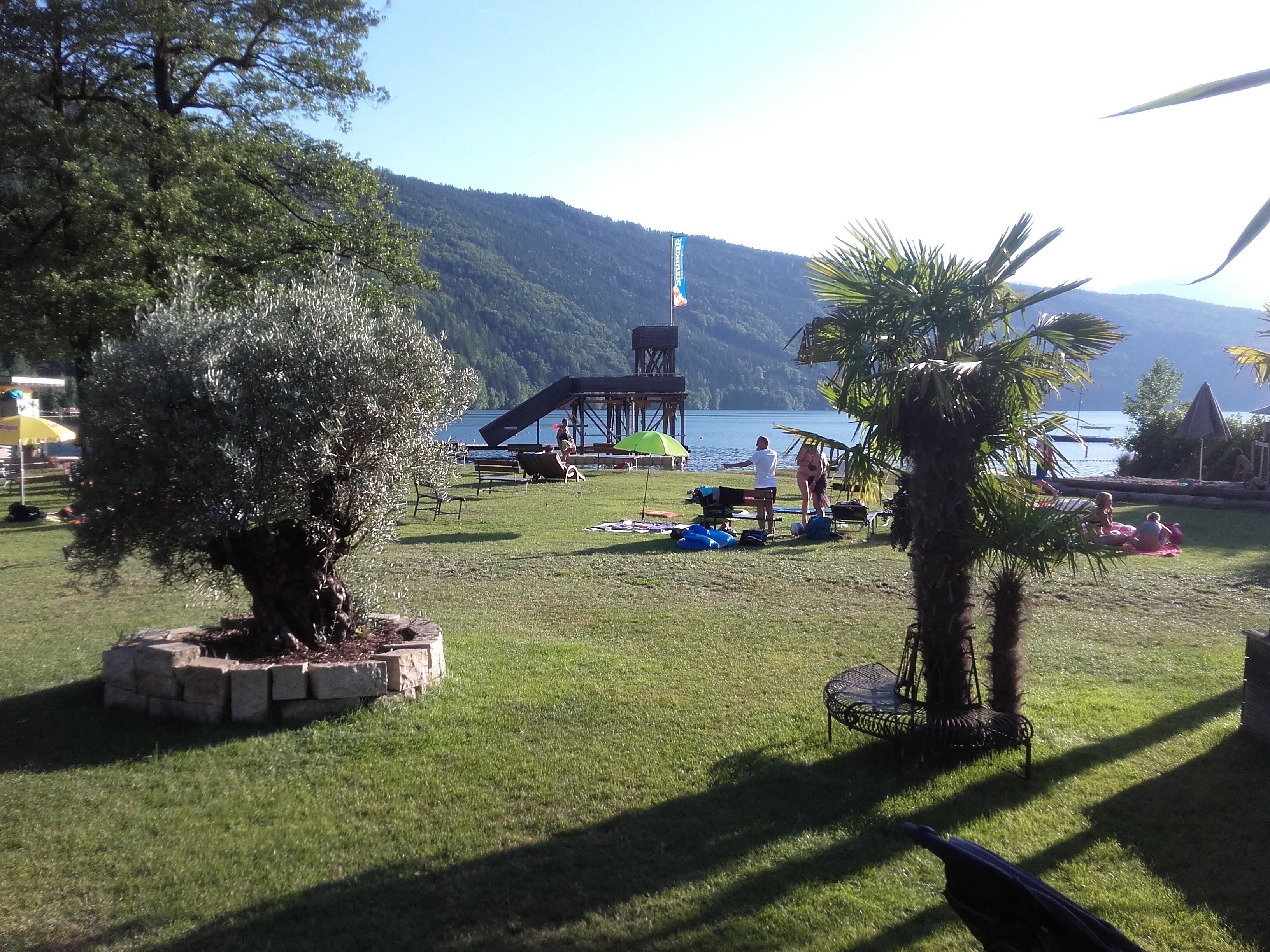 A grassy area with a stage, seating, and a view of a lake and mountains.