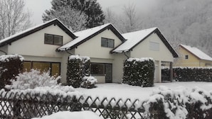 Una casa de dos pisos con techo nevado y patio cercado.