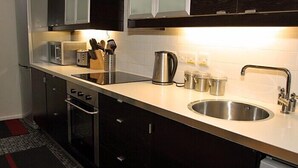 A modern kitchen with stainless steel appliances, a sink, and a countertop with a knife block and cups. - Lovely renovated Stone Cottage & Garden, great location Central Yorkshire (TADCASTER)