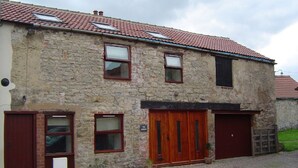 A stone building with a tiled roof, two windows, and a wooden door. - Lovely renovated Stone Cottage & Garden, great location Central Yorkshire (TADCASTER)