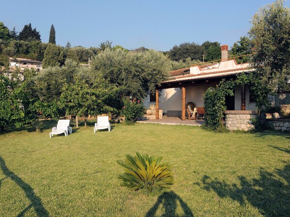 Una casa con patio, dos sillones blancos y un muro de piedra.