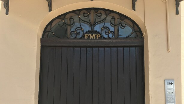 Una puerta doble negra con un arco de metal decorativo encima y una placa que dice "EMP".