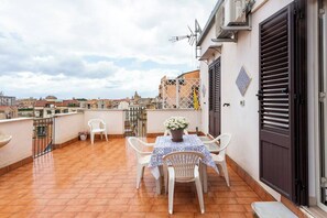A terrace with a table and chairs, a potted plant, and a view of the cityscape. - Frank's house - flat with terrace in the centre (Palermo)