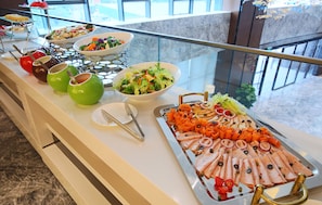 A buffet with various food items and colorful drinks.