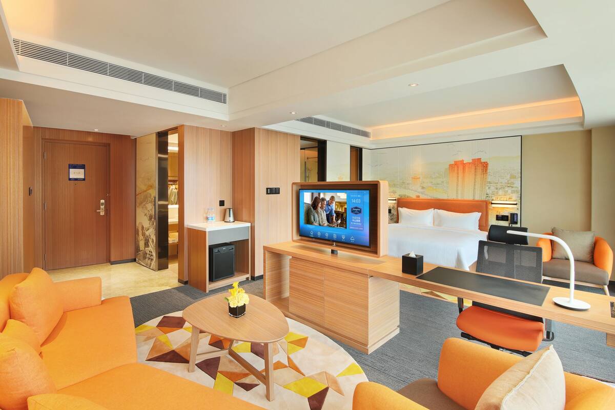 Una habitación de hotel con televisión, cama, escritorio, silla y sofá.