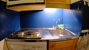 Une cuisine compacte équipée d’un four à micro-ondes encastré, d’un évier et d’un lave-vaisselle.