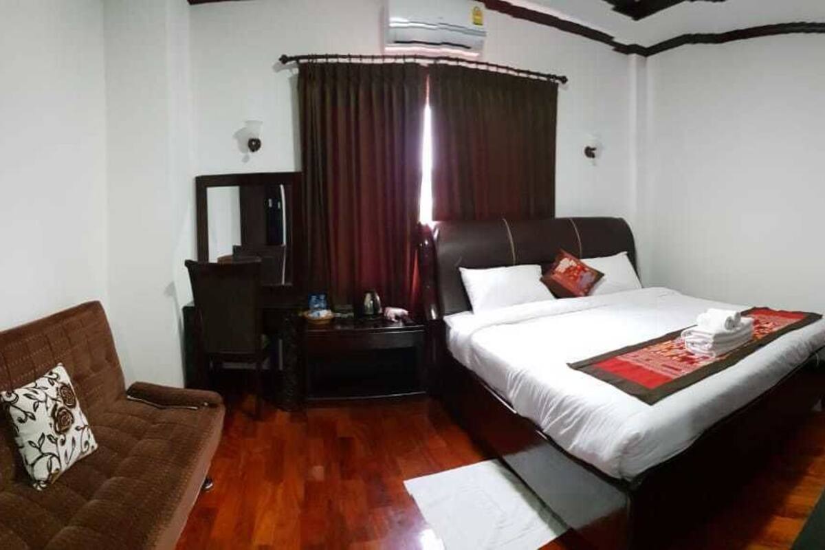 Ein Hotelzimmer mit Bett, braunem Sofa, Schreibtisch und Stuhl.