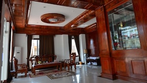 Un salón amplio con techo de madera, un ventanal grande y una zona de estar con sofá y sillones.