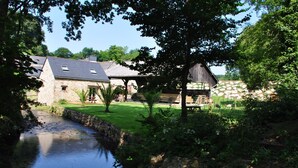 Ein Steinhaus mit einer Rasenfläche und einem kleinen Bach.