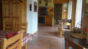 Une cuisine rustique avec des meubles en bois, un sol carrelé et un coin repas agrémenté d’une nappe à carreaux.