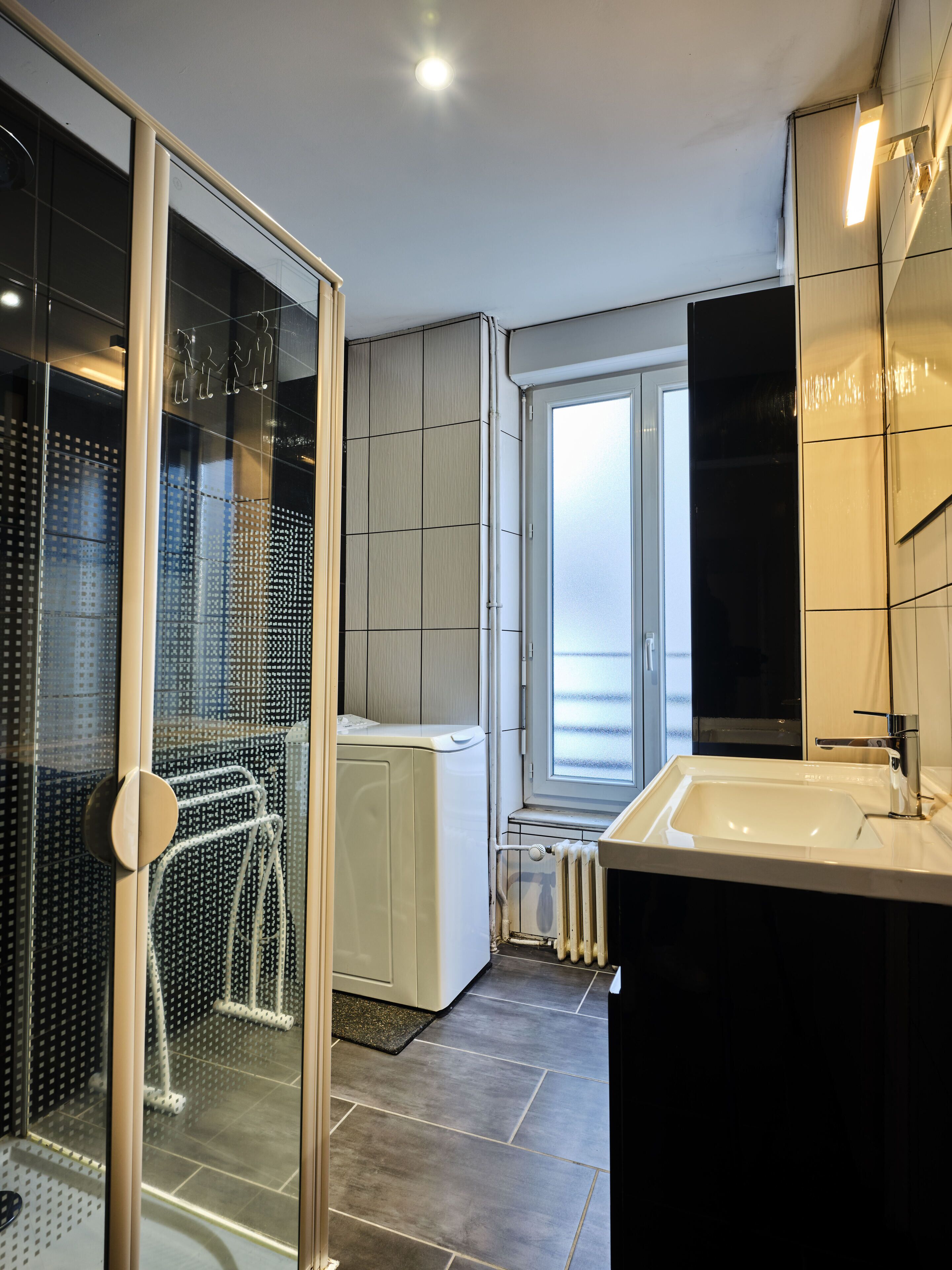 A modern bathroom with a glass shower enclosure, a built-in sink, and a window providing natural light.