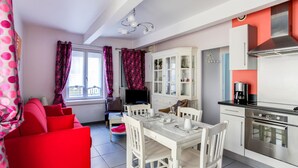 Une cuisine moderne avec des meubles blancs, une hotte en acier inoxydable et un coin repas comprenant une table et des chaises blanches.