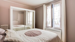 Une chambre à coucher avec un lit, une chaise, une armoire et une fenêtre avec des rideaux.