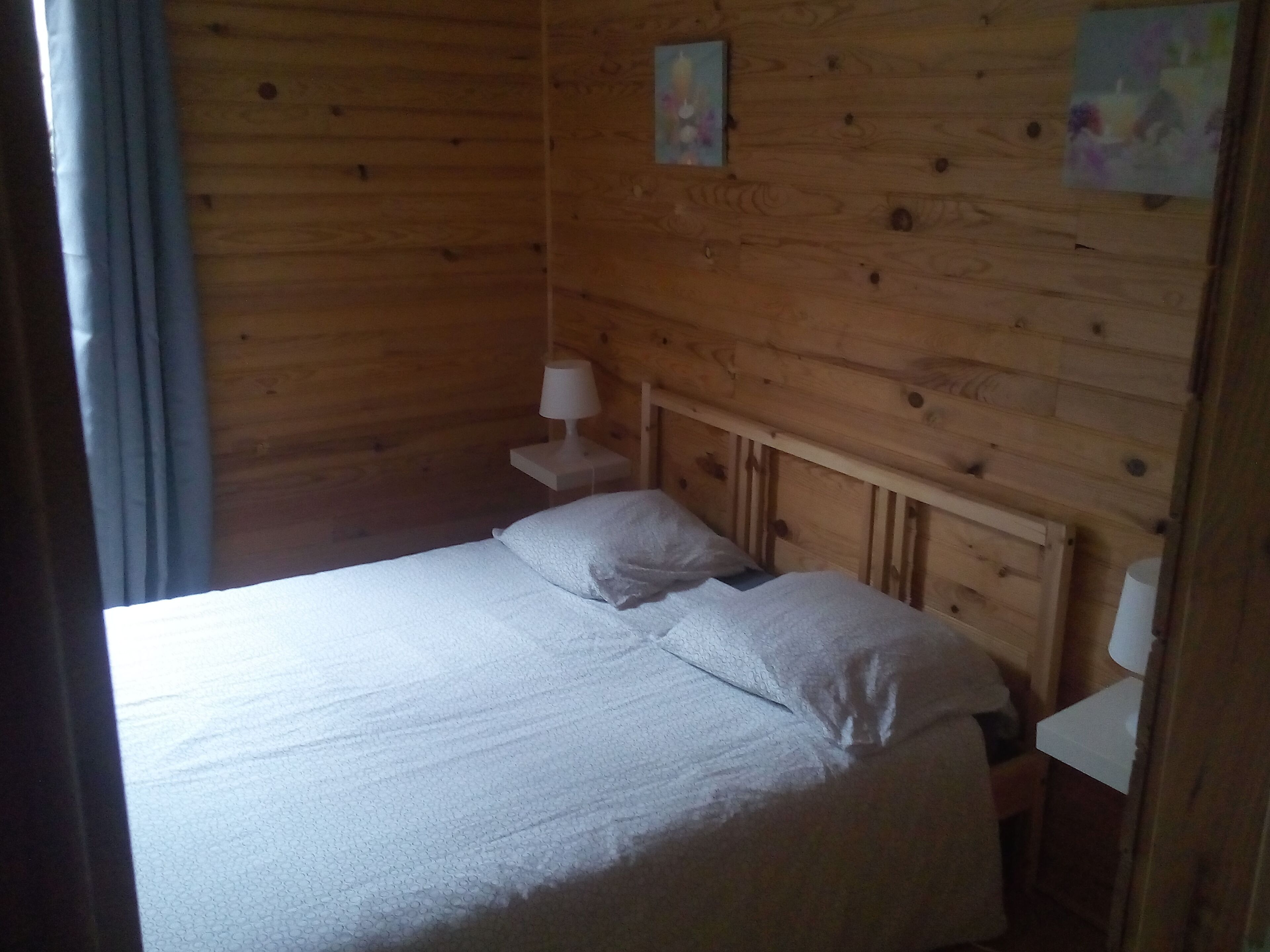 Een kamer met houten vloeren, een bed, een nachtkastje en een lamp.
