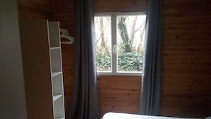 Une chambre à coucher avec un lit, une armoire en bois et une fenêtre avec des rideaux.