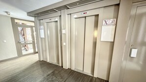 A hallway with four elevator doors, each with a sign indicating no smoking. - Standing Apartment 4 people + Parking + Ski locker - Arcs 1800 (Bourg-Saint-Maurice)